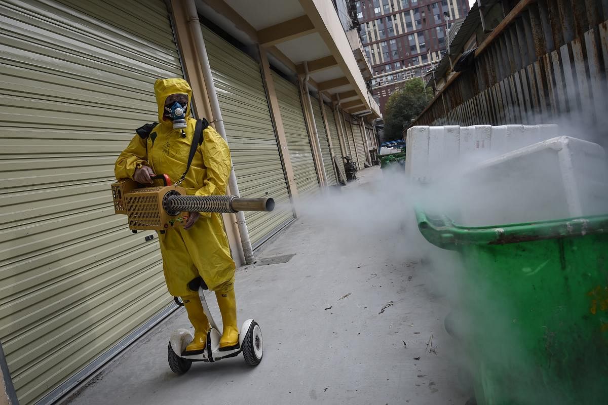 A medical staff member sprays disinfectant at a residential area in Wuhan in China. (AFP Photo)