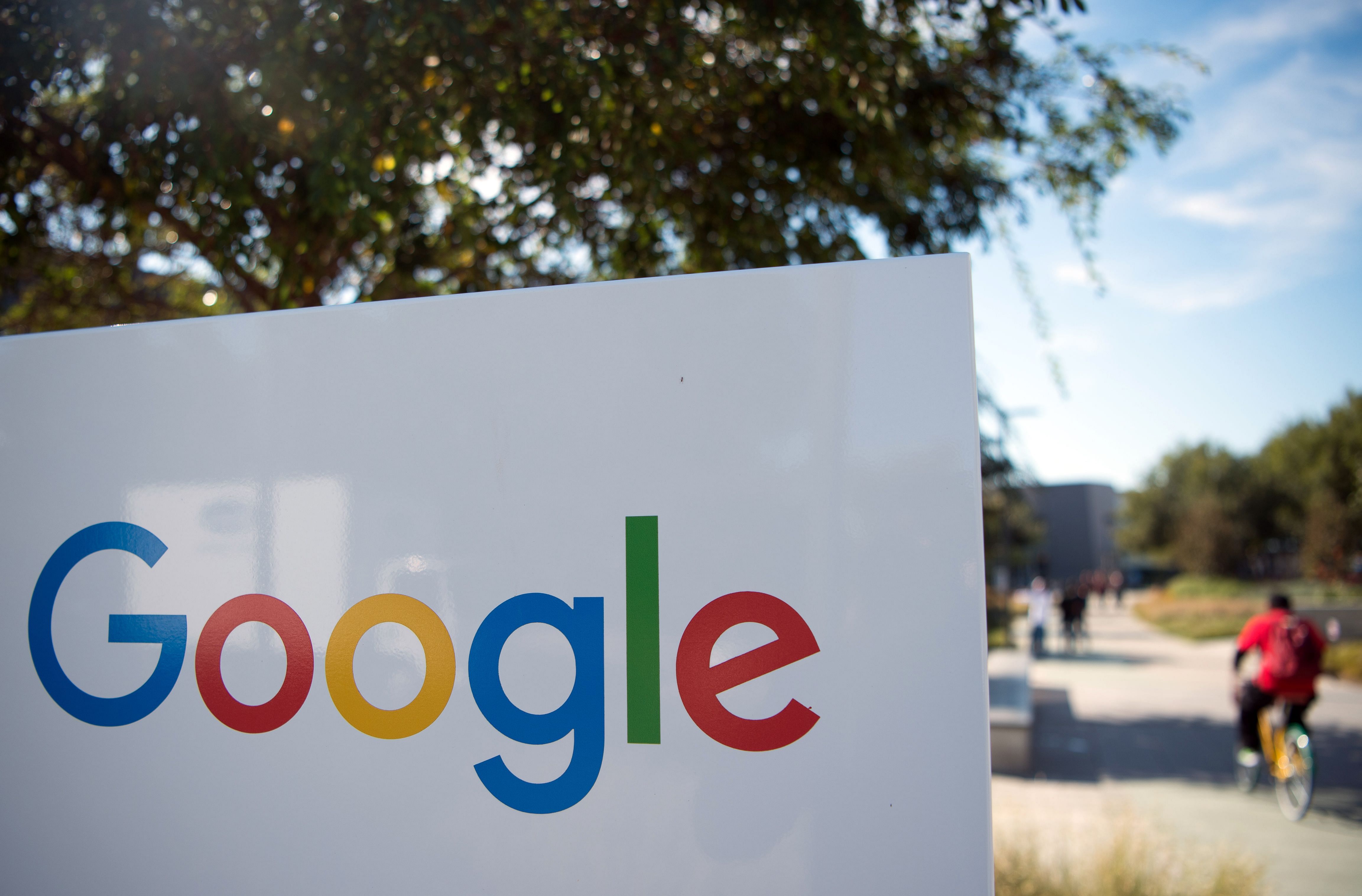 In this file photo taken on November 4, 2016 a man rides a bike past a Google sign and logo at the Googleplex in Menlo Park, California. (Credit: AFP)