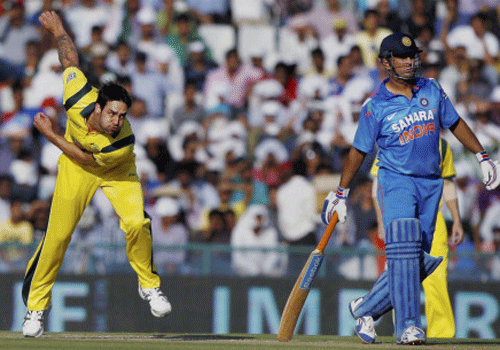 Australian bowler Johnson in action as Indian batsman MS Dhoni looks on during their 3rd ODI cricket match at PCA stadium in Mohali on Saturday. PTI Photo