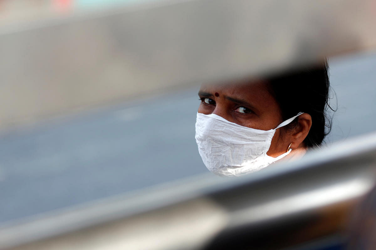 A woman wearing a protective mask waits for a bus to return to her village during lockdown by the authorities to limit the spreading of coronavirus disease (COVID-19), in New Delhi. Credit: Reuters Photo