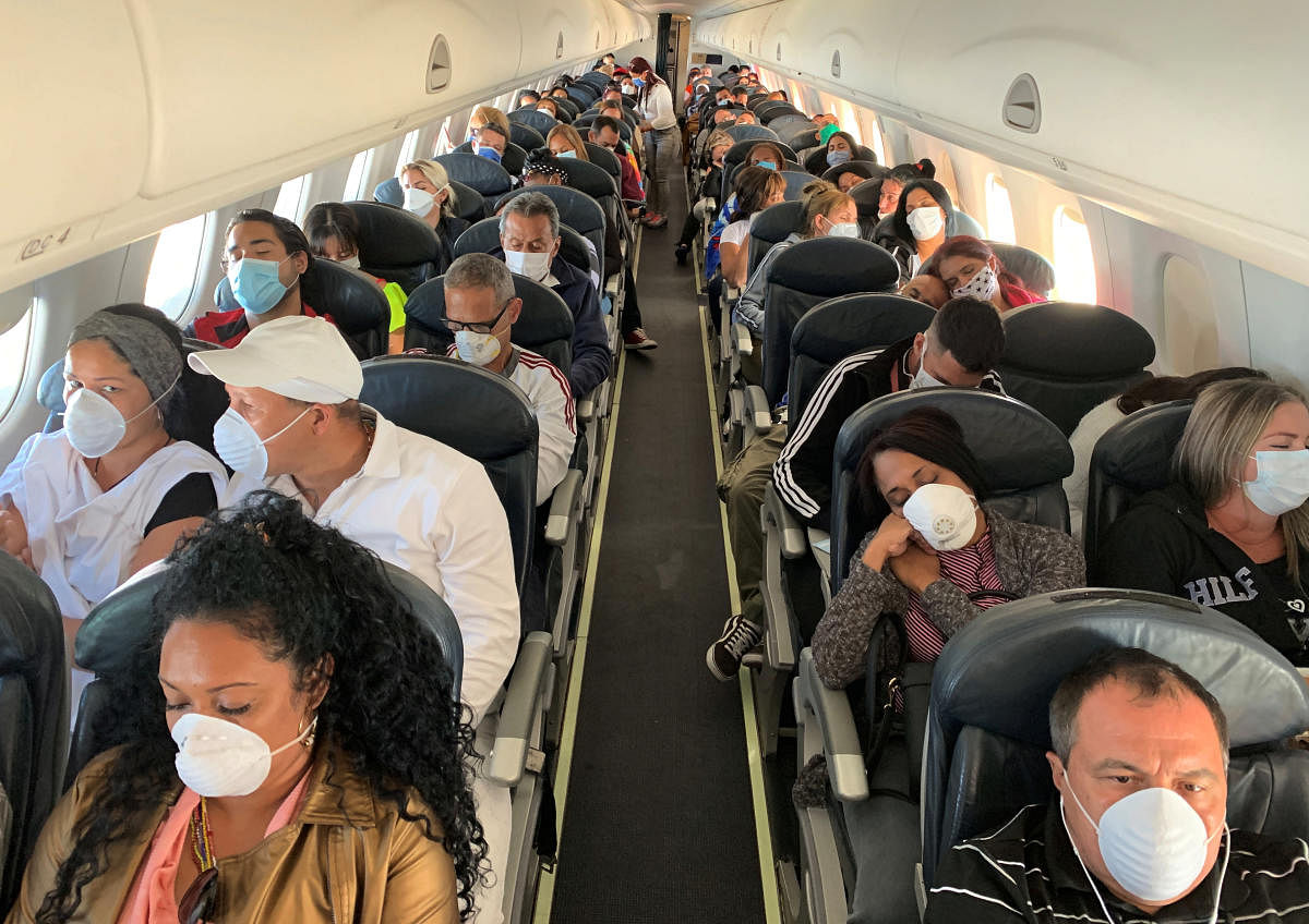 People wear protective masks in response to the spreading of coronavirus (COVID-19), during a flight between Caracas Venezuela and la Havana. (Reuters photo)