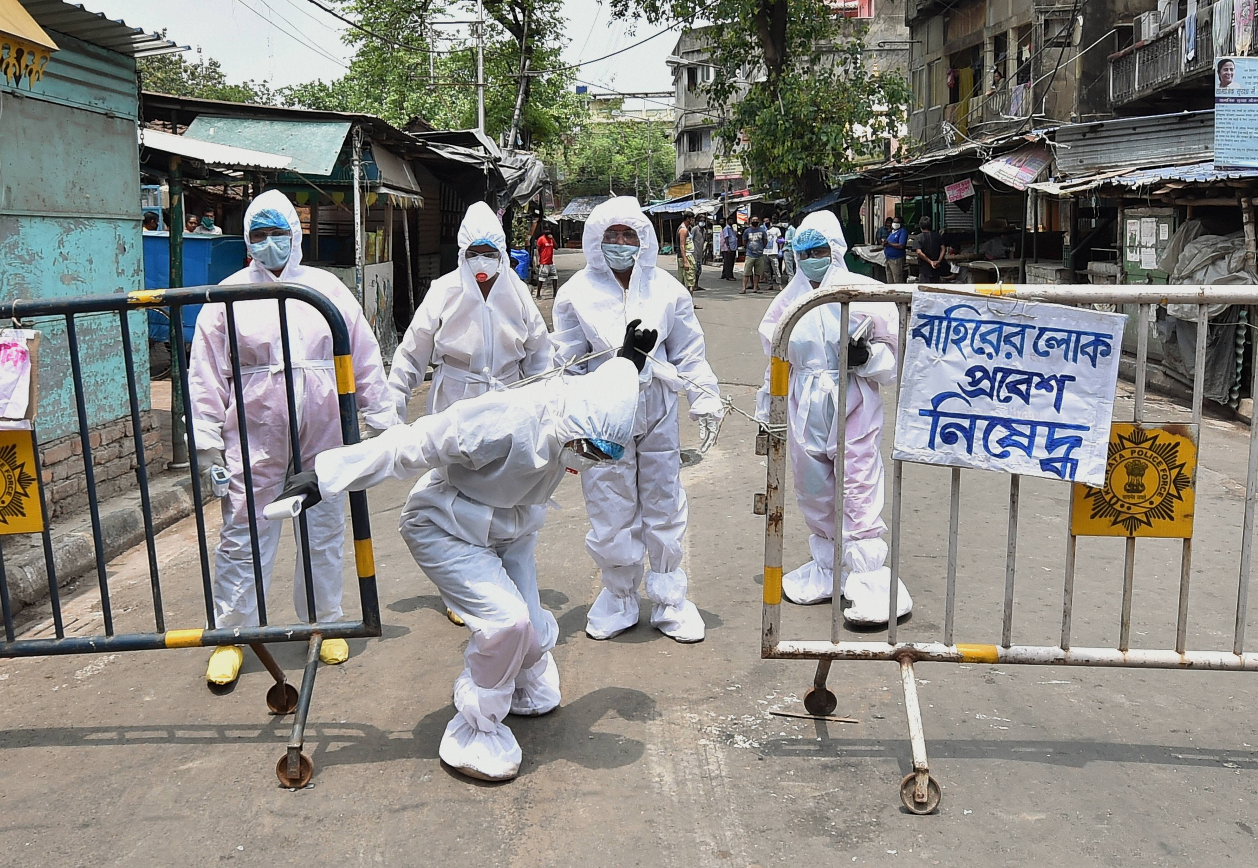 Health workers wearing protective gear arrive at a containment zone for door-to-door thermal screening to detect COVID-19 positive cases, amid the ongoing nationwide lockdown, in Kolkata. (Credit: PTI Photo)