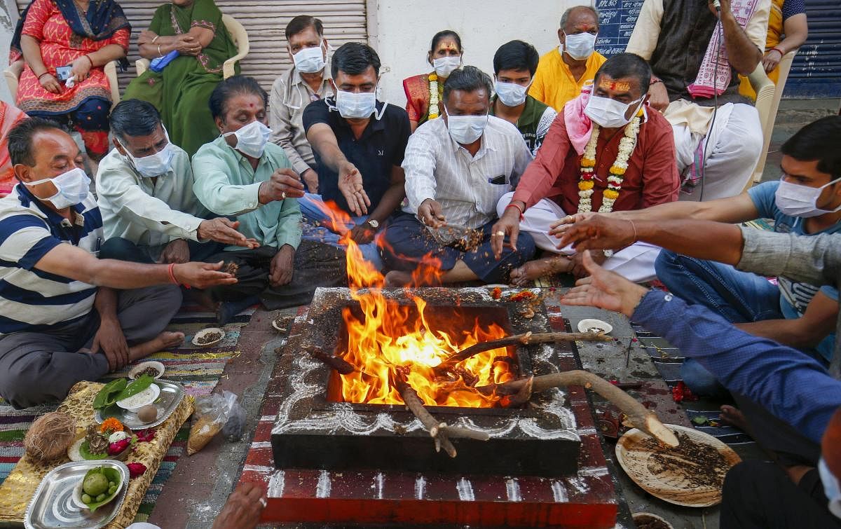 Residents wearing facemasks participate in a prayer for speedy recovery of people affected by COVID-19 coronavirus, in Ahmedabad, Friday, March 13, 2020. (PTI Photo)
