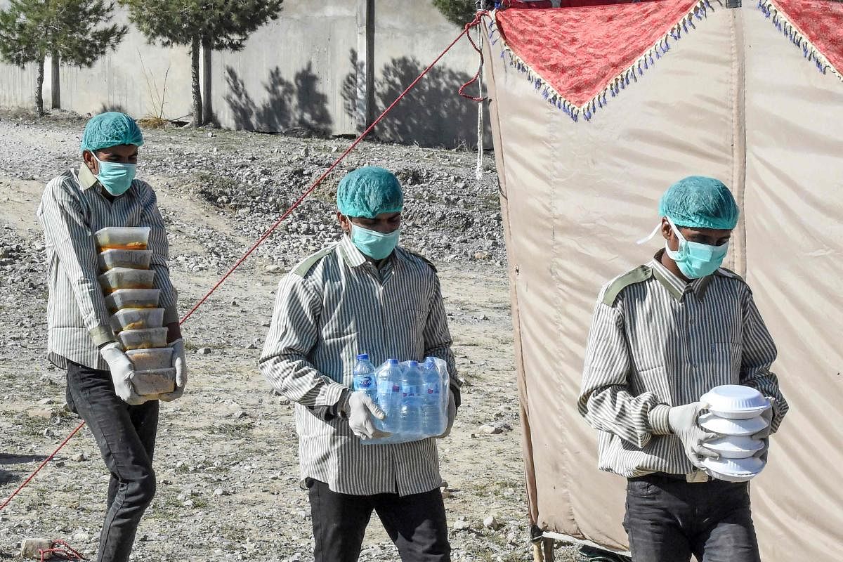 Workers of the Provincial Disaster Management Authority (PDMA) of Balochistan carry food for pilgrims at a quarantine camp prepared for people returning from Iran via the Pakistan-Iran border town of Taftan to prevent the spread the COVID-19 coronavirus, on the outskirts of Quetta on March 13, 2020. (Photo by AFP)