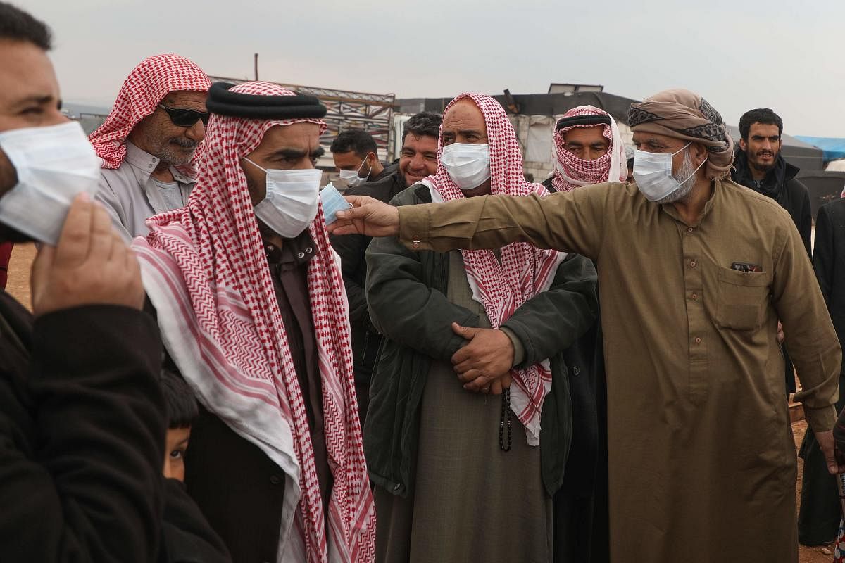 A Syrian man distributes face masks during an awareness workshop on Coronavirus (COVID-19) held by Doctor Ali Ghazal at a camp for displaced people in Atme town in Syria's northwestern Idlib province, near the border with Turkey, on March 14, 2020. (AFP P