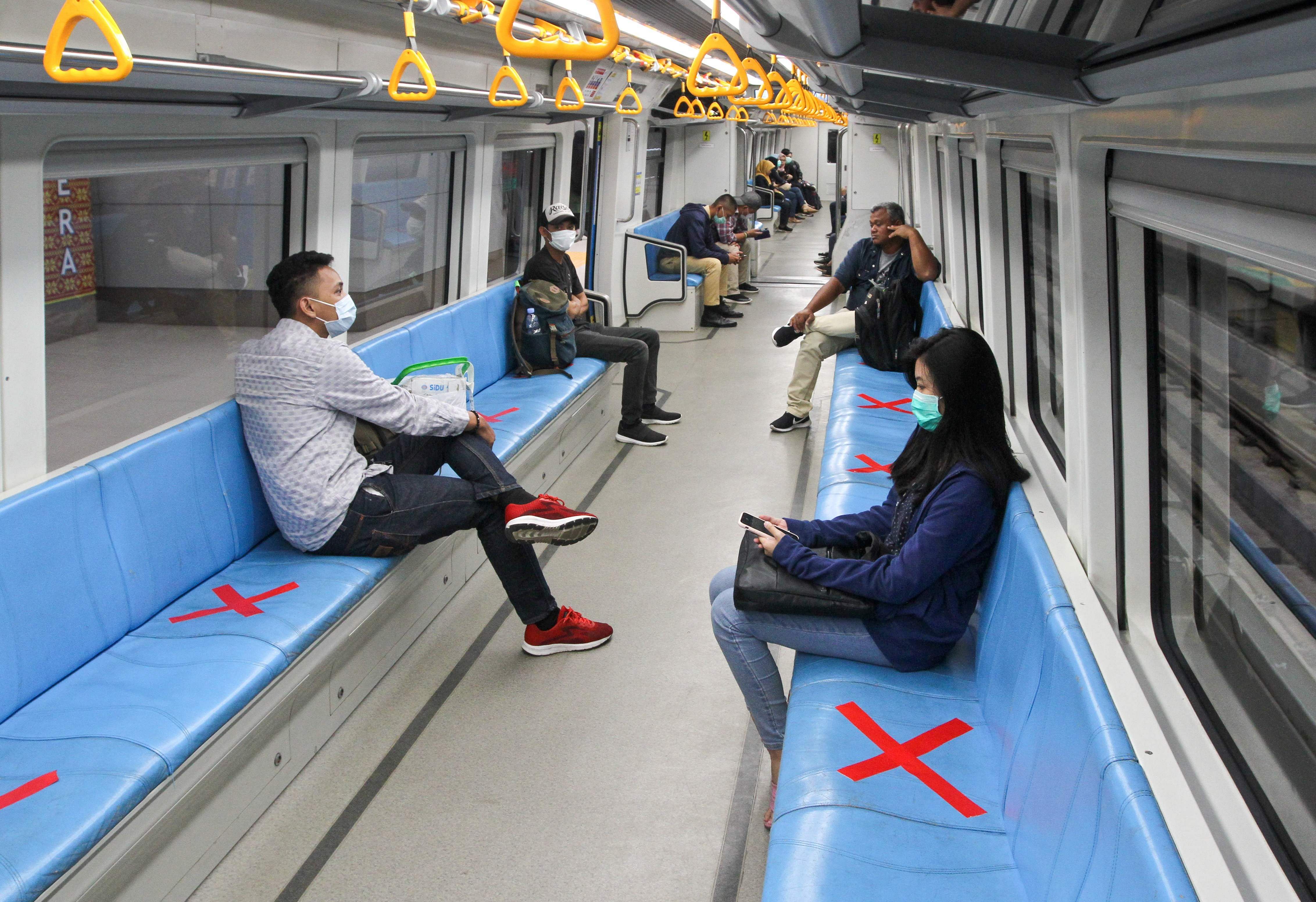 People sit on designated areas decided by red cross marks to ensure social distancing inside a light rapid transit train in Palembang, South Sumatra on March 20, 2020, amid concerns of the COVID-19 coronavirus outbreak.. (AFP Photo)
