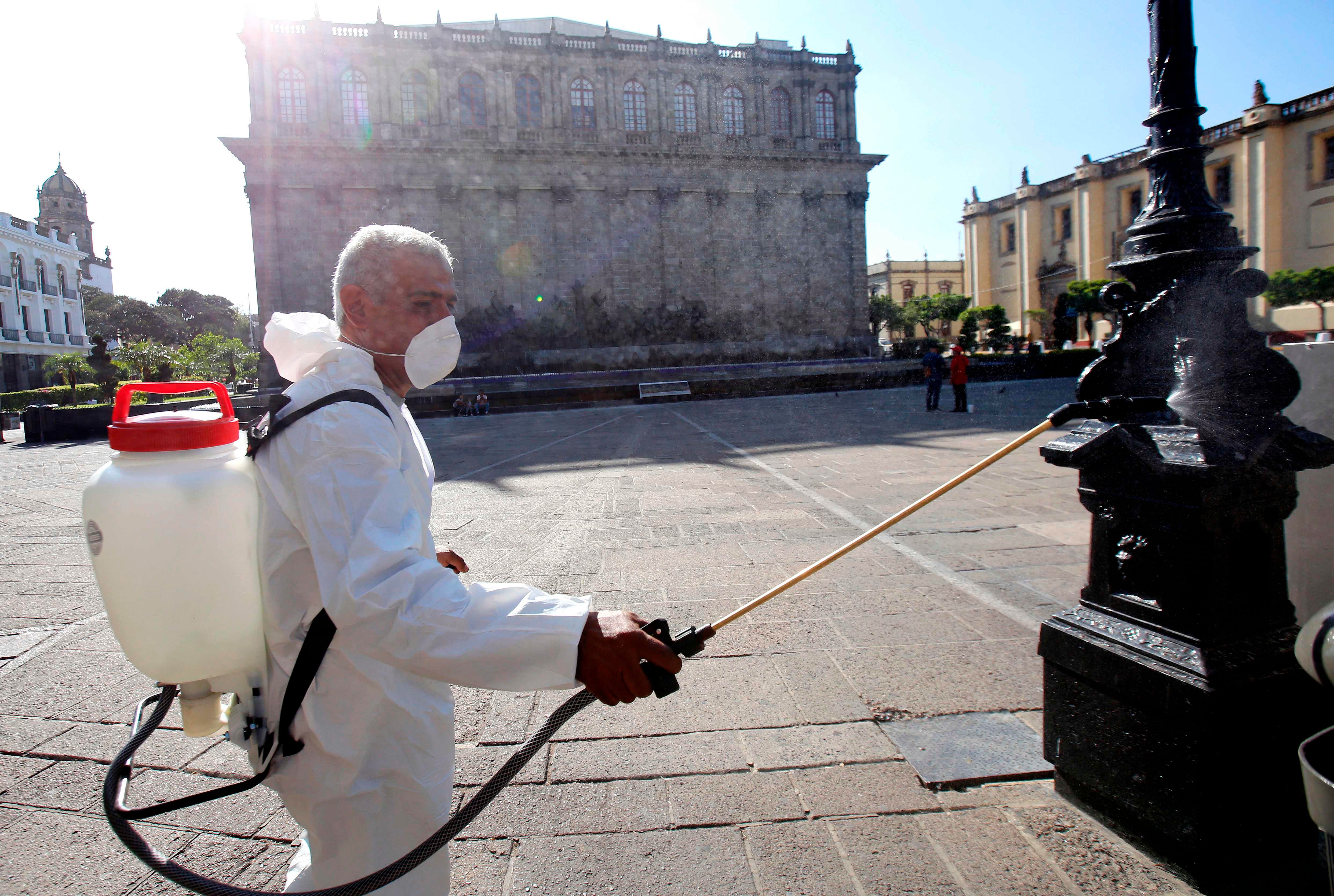 A worker wearing a protective suit sprays disinfectant during a campaign to sanitize public spaces as a preventive measure against the spread of the new coronavirus, COVID-19, in Guadalajara, Mexico. (Credit: AFP)
