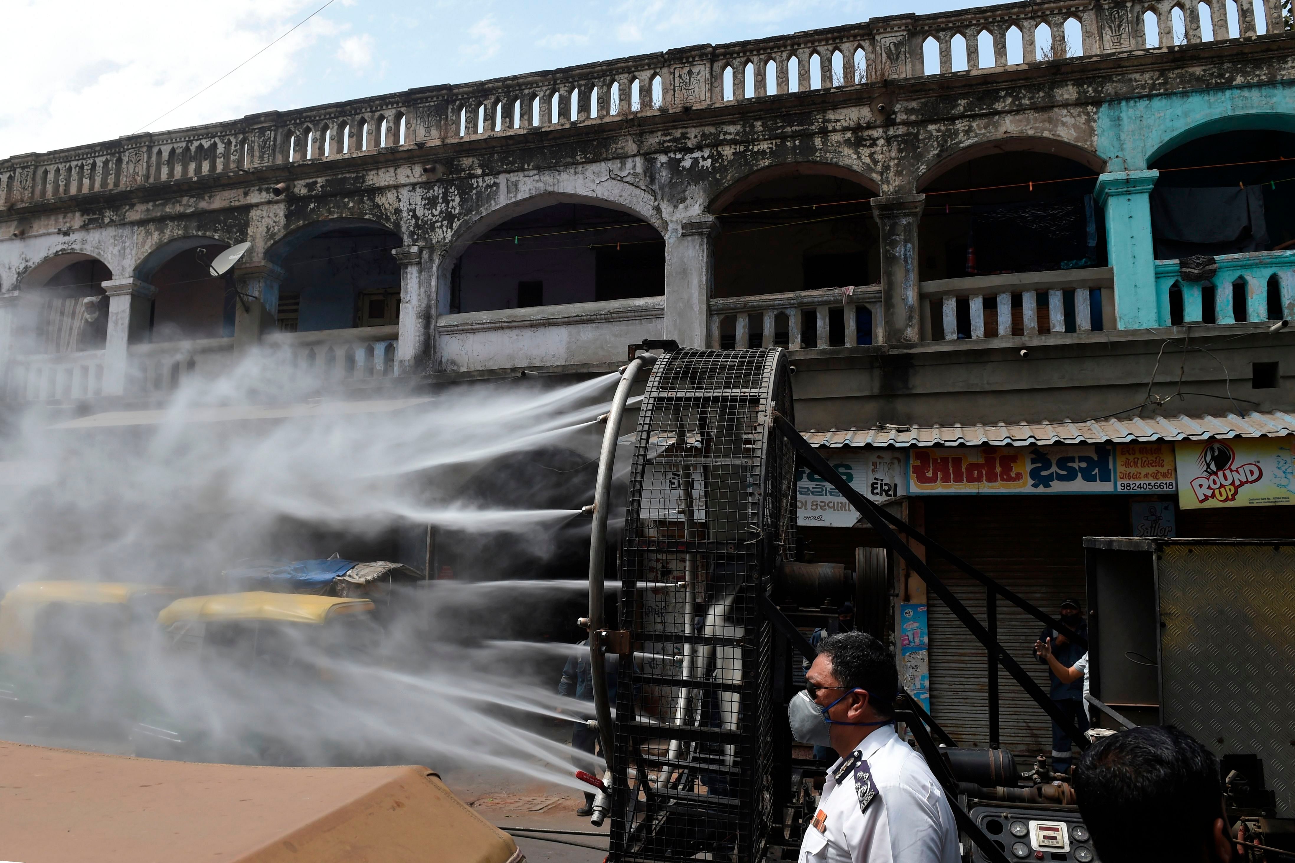 Firefighters from Ahmedabad Fire and Emergency Services spray disinfectant along a street during Gujarat's government-imposed lockdown. (Credit: AFP)