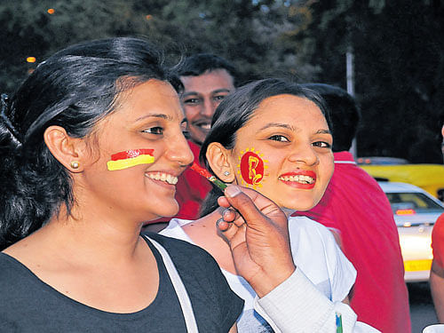 Cricket fans get their favourite team logo painted on their faces near Chinnaswamy Stadium ahead of an IPL match between  Royal Challengers Bangalore and Delhi Daredevils on  Sunday. dh photo