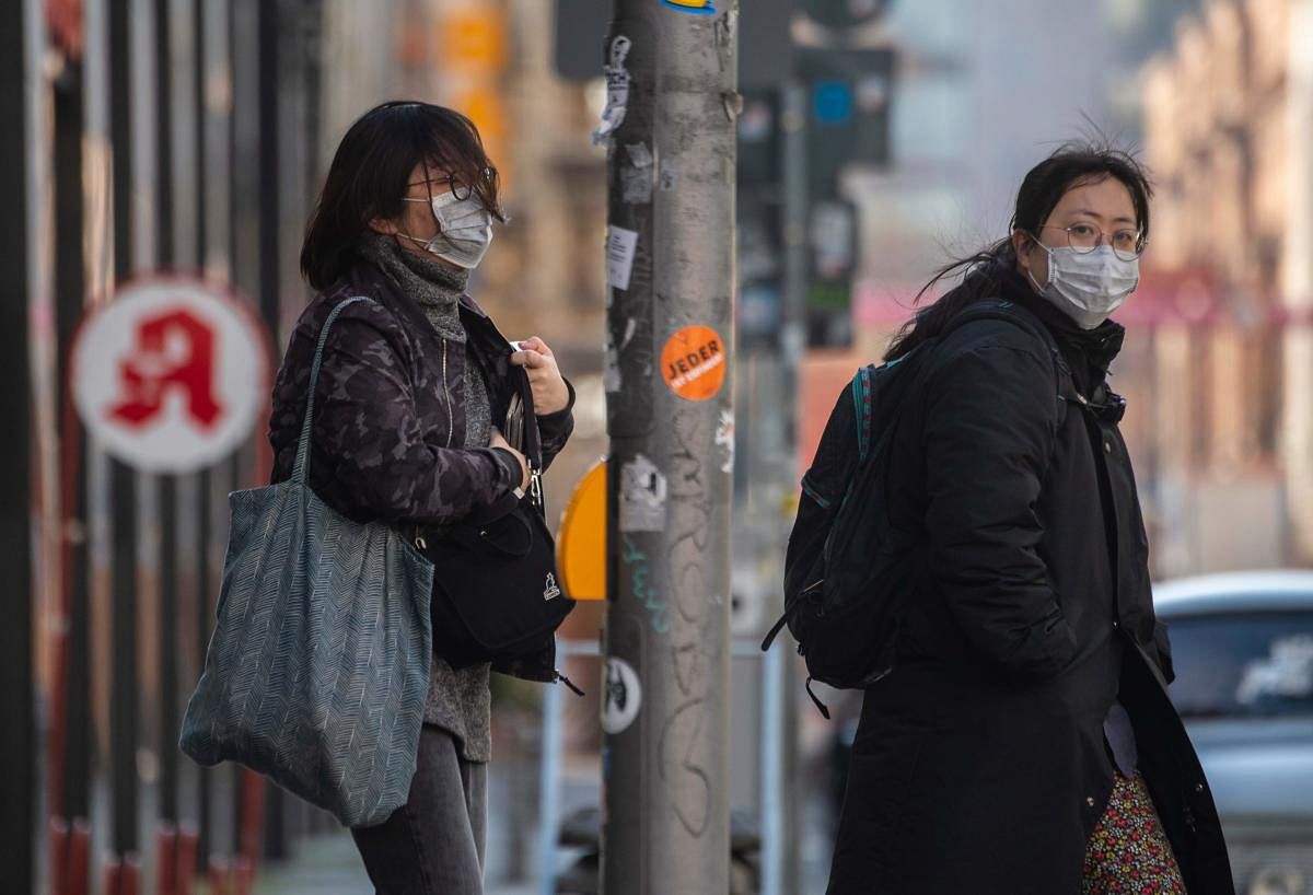 People wearing surgical masks cross a street in Berlin's Mitte district on March 25, 2020, amid a new coronavirus COVID-19 pandemic. Credit: AFP Photo
