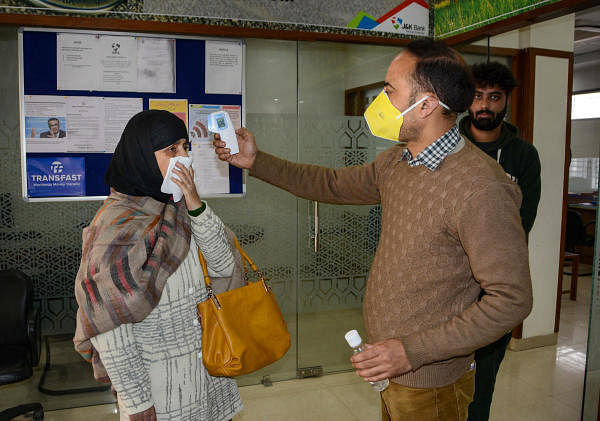 An official measures the temperature of a visitor using an infrared thermometer at the entrance of a bank, following the outbreak of coronavirus, in Srinagar, Monday March 23, 2020. (PTI Photo)