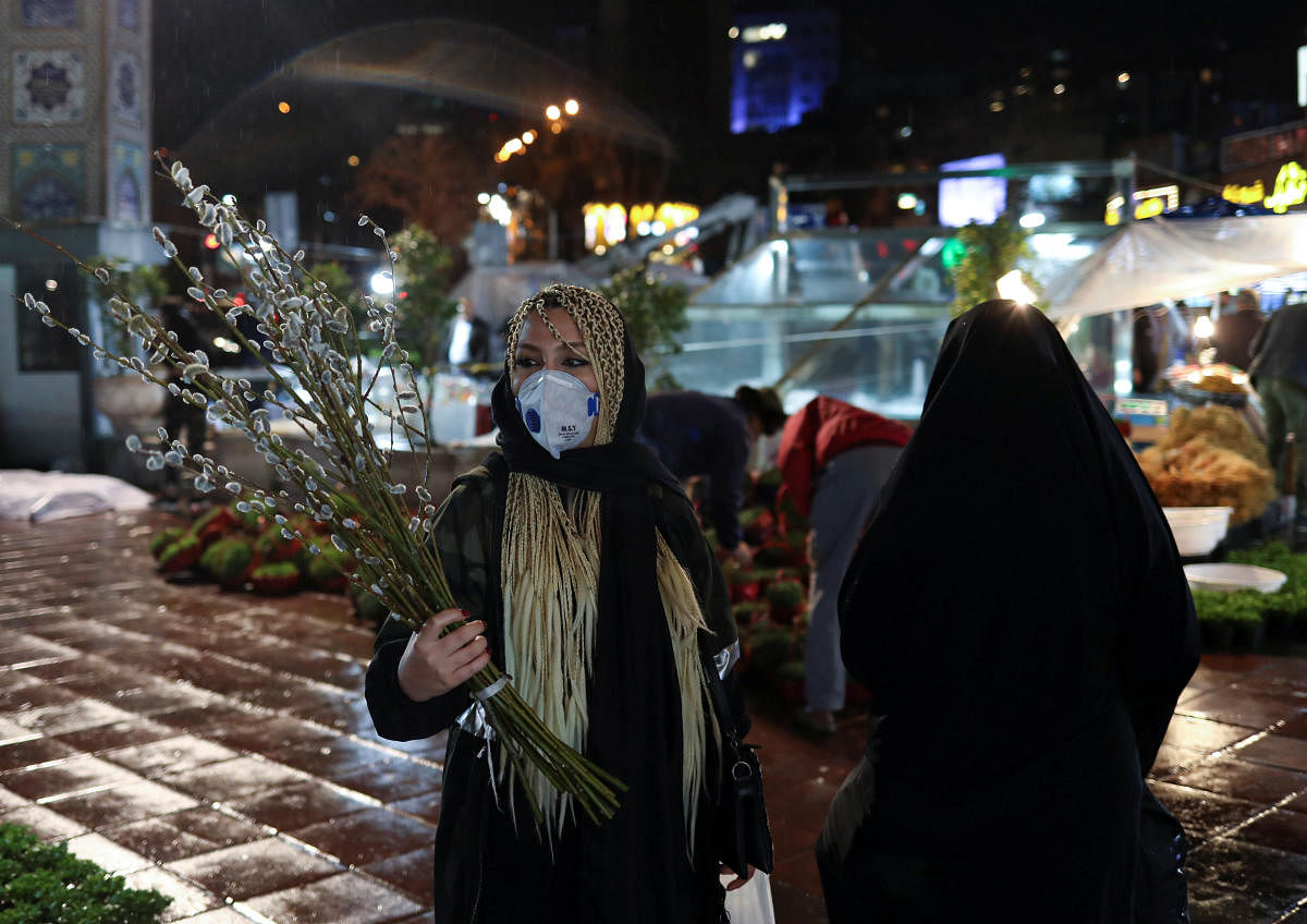 An Iranian woman wears a protective face mask, amid fear of coronavirus disease (COVID-19), as she carries catkins, ahead of the Iranian New Year Nowruz, March 20, in Tajrish square northern Tehran. Credit: Reuters Photo
