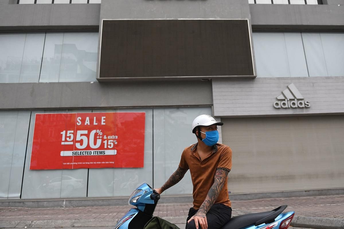 A man, wearing a face mask as a preventive measure against the spread of the COVID-19 novel coronavirus, stands outside a closed shop in Hanoi (AFP Photo)