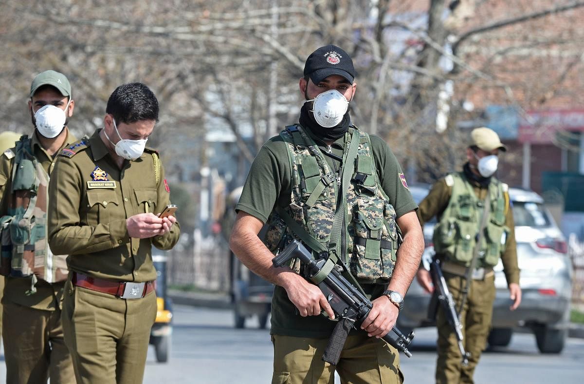 Policemen wearing facemasks as a preventive measure against the COVID-19 coronavirus guard a street in Srinagar (AFP Photo)