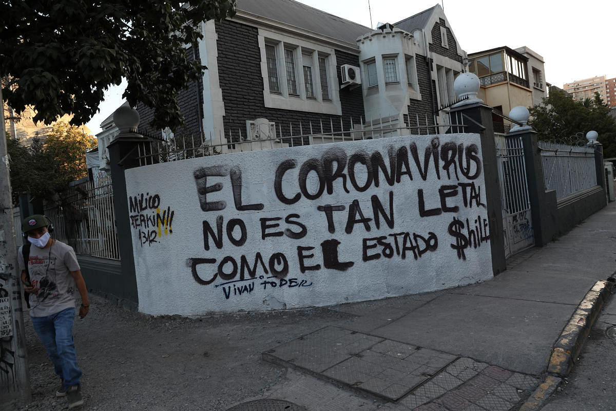 A man wearing a protective face mask walks past a graffiti reading "Coronavirus is not as lethal as the Chilean state" during the outbreak of coronavirus disease (COVID-19) in Santiago, Chile  (Reuters Photo)