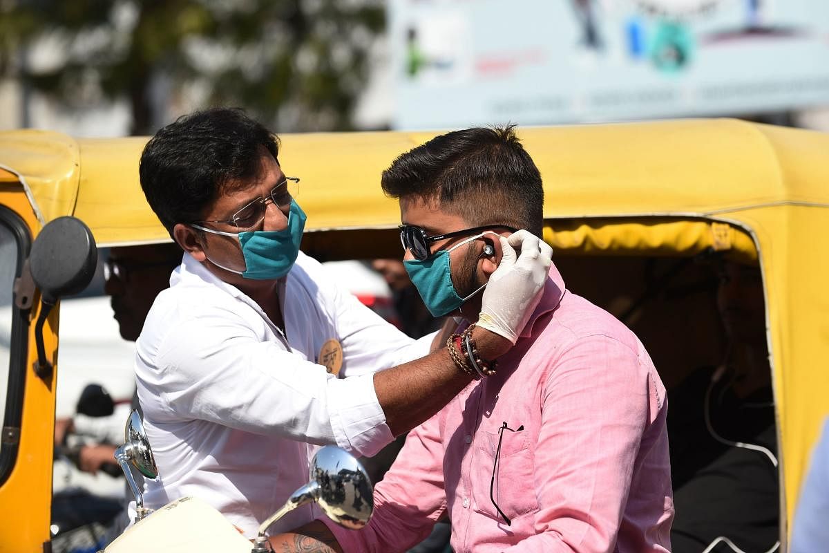 A volunteer of the Humf NGO adjusts a free facemask to a motorist during a facemaks donation campaing amid concerns over the spead of the COVID-19 coronavirus, in Ahmedabad on March 17, 2020. (AFP Photo)