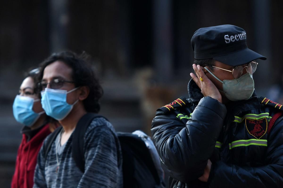 Visitors and a security guard wear facemasks as a preventive measure against the COVID-19 coronavirus at Patan durbar square in Lalitpur on March 17, 2020. Credit: AFP Photo