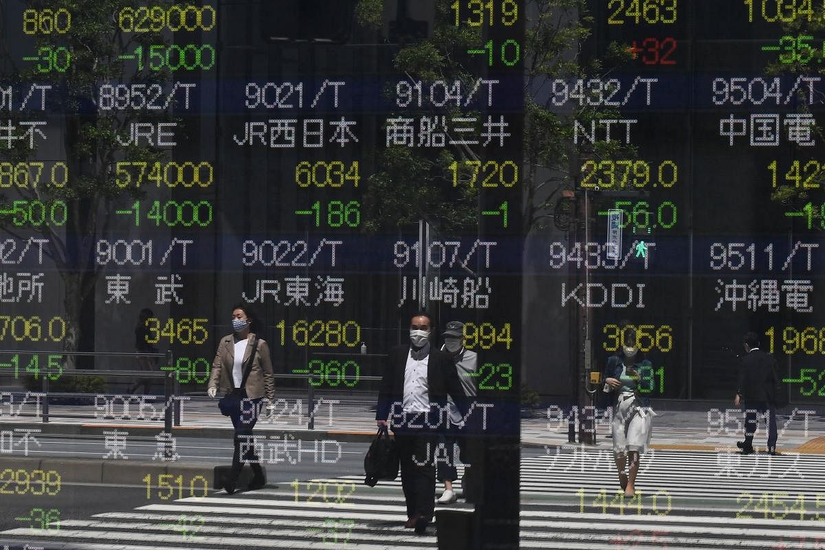  Pedestrians are seen reflected in a quotation board displaying stock prices on the Tokyo Stock Exchange in Tokyo on May 7, 2020. Credit: AFP Photo