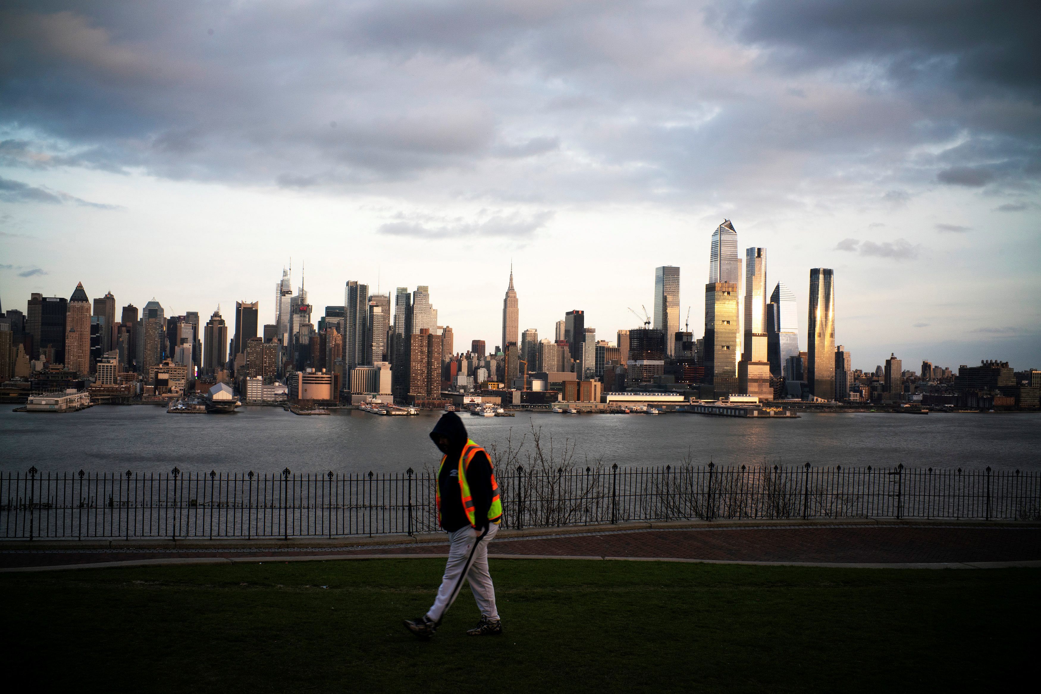 The Empire State Building and the skyline of New York are seen while a man walks around a local park in Weehawken, New Jersey. (Credit: Reuters)