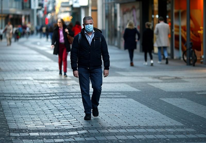A man wearing a protective mask walks in the main shopping street as shops are closed during the spread of the coronavirus disease (COVID-19) in Cologne, Germany. (Reuters Photo)