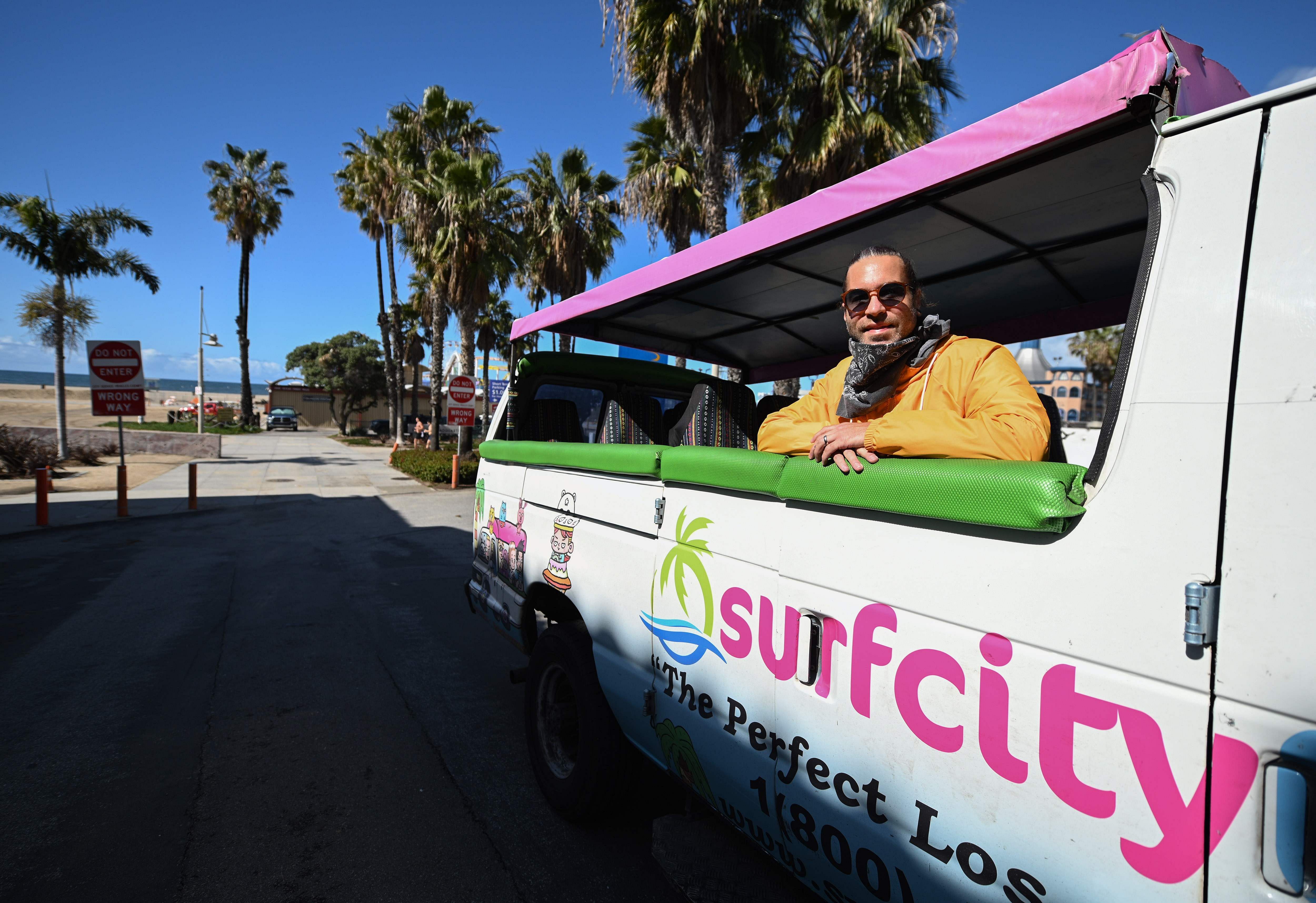 Adam Duford, owner of Surf City Tours, poses for a photo in one of his tour buses on an empty street near the beach in Santa Monica, California. (Credit: AFP)