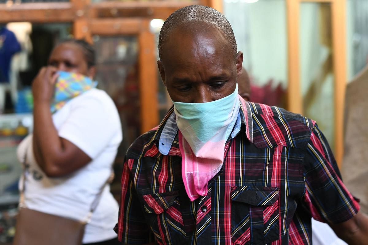 A curio trader covers his nose as a staff member of Kenya's Ministry of Health sprays disinfectant at the city market to curb the spread of the COVID-19 coronavirus at the Gikomba Market in Nairobi, on March 24, 2020.  Credit: AFP Photo