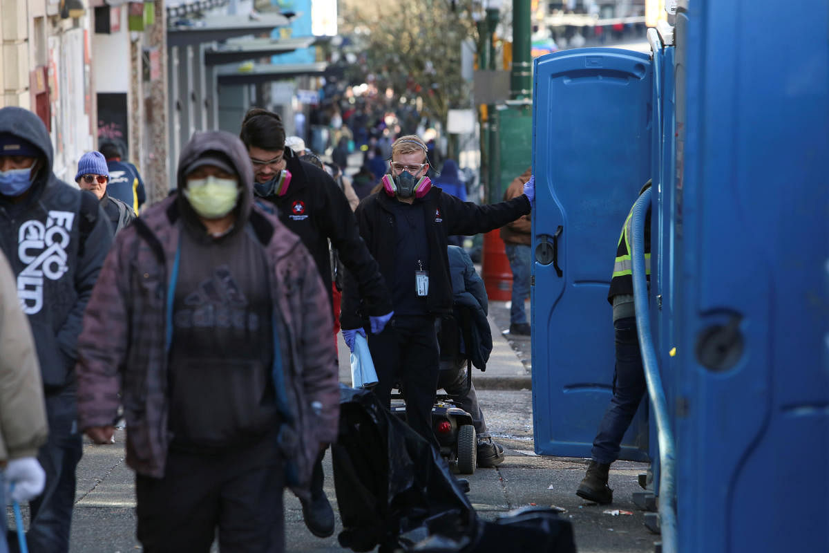 Contractors wearing protective masks clean a series of portable toilets installed along Hastings Street in Vancouver's Downtown Eastside, as the number of coronavirus disease (COVID-19) cases continues to grow in Vancouver, British Columbia, Canada (Reuters Photo)