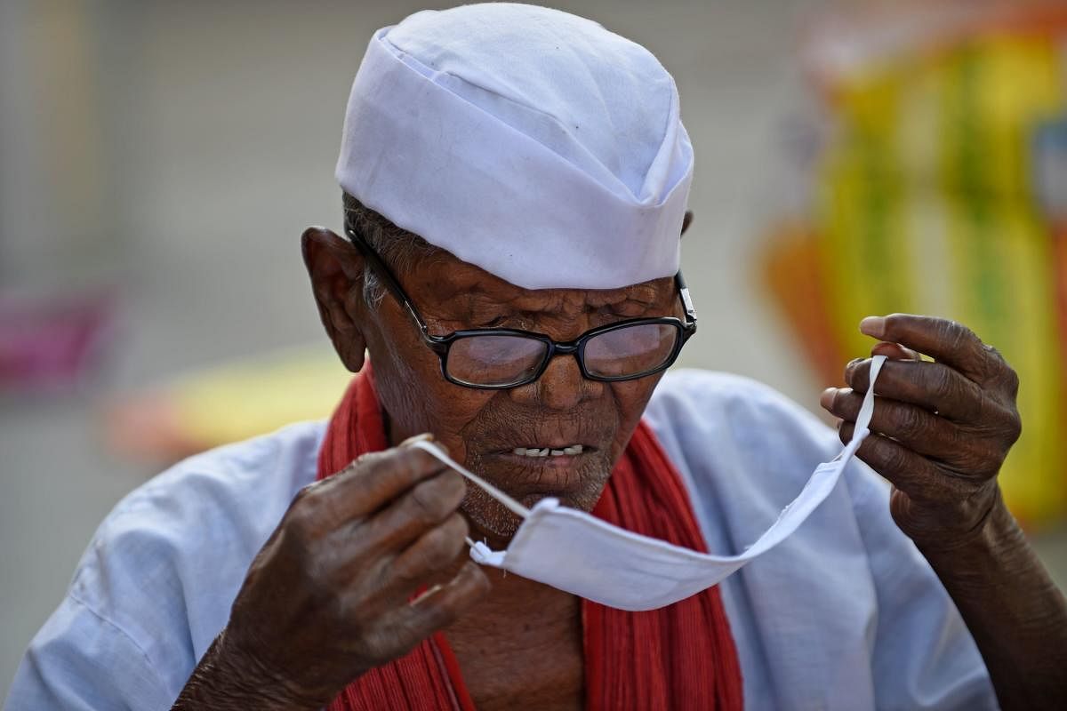 A leprosy-affected man, looks at a facemask being distributed by a non-governmental organisation amid concerns over the spread of the COVID-19 novel coronavirus, at Gandhi Leprosy Seva Sangh, a rehabilitation centre for leprosy patients, in Ahmedabad on March 21, 2020. (Photo by SAM PANTHAKY / AFP)