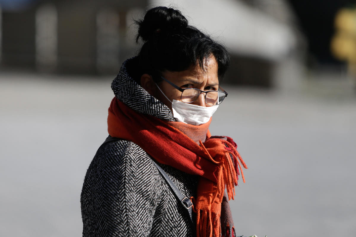 A woman wearing a protective mask as a preventive measure walks on March 25, 2020, in Brussels, as a strict lockdown comes into effect to stop the spread of the COVID-19, the disease caused by the novel coronavirus. (Photo by Aris Oikonomou / AFP)