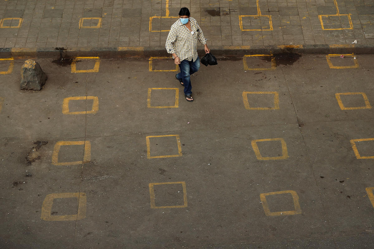 A man wearing a protective mask walks on a street with squares painted on it for maintaining safe distance, to limit the spread of the coronavirus disease (COVID-19) in Mumbai, India March 28, 2020. Credit: Reuters File Photo