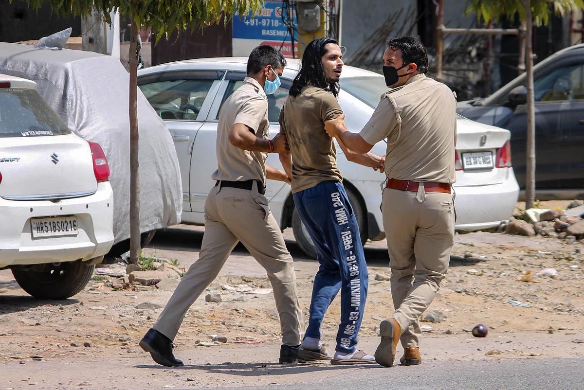 Police personnel detain a commuter after he tries to cross barricades during lockdown in the wake of coronavirus pandemic, in Faridabad (PTI photo)