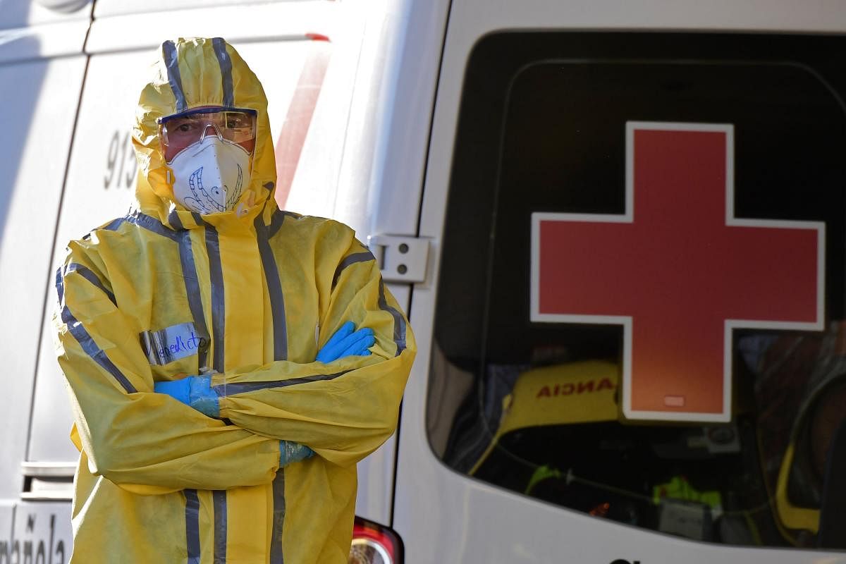A Civil Defence member stands next to a Red Cross ambulance outside the Severo Ochoa hospital in Leganes, on March 26, 2020.  Credit: AFP Photo