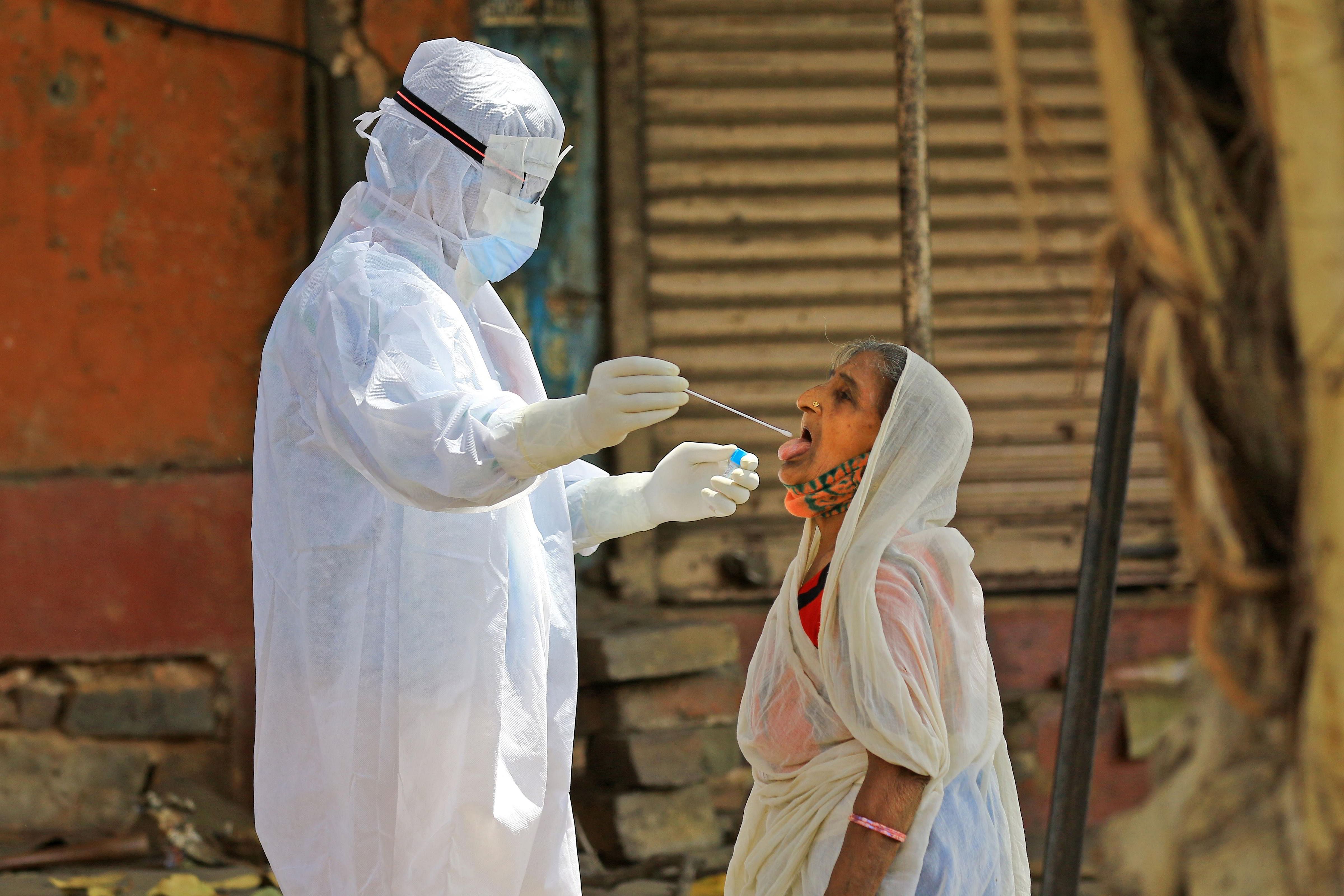 A medic collects a swab sample of an elderly woman during a door-to-door examination of COVID-19 amid a nationwide lockdown imposed in the wake of coronavirus pandemic. (PTI photo)