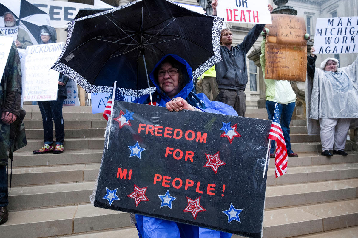 A woman holds a placard during a protest against Governor Gretchen Whitmer's extended stay-at-home orders intended to slow the spread of the coronavirus disease (COVID-19) at the Capitol building in Lansing, Michigan (Reuters Photo)