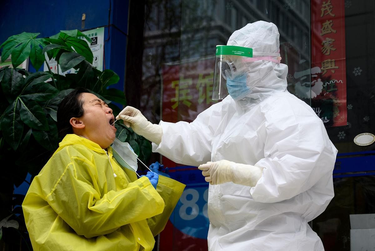 A medical worker wearing a hazmat suit get swabs on a woman to check if she has coronavirus on a health clinic in Wuhan, in China's central Hubei province on March 28, 2020. (Photo by NOEL CELIS / AFP)