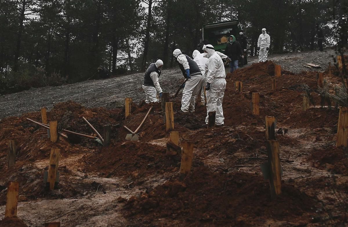 Health officials dig a grave in a newly prepared cemetery for the burial of coronavirus victims, in Istanbul's Beykoz district. AP/PTI