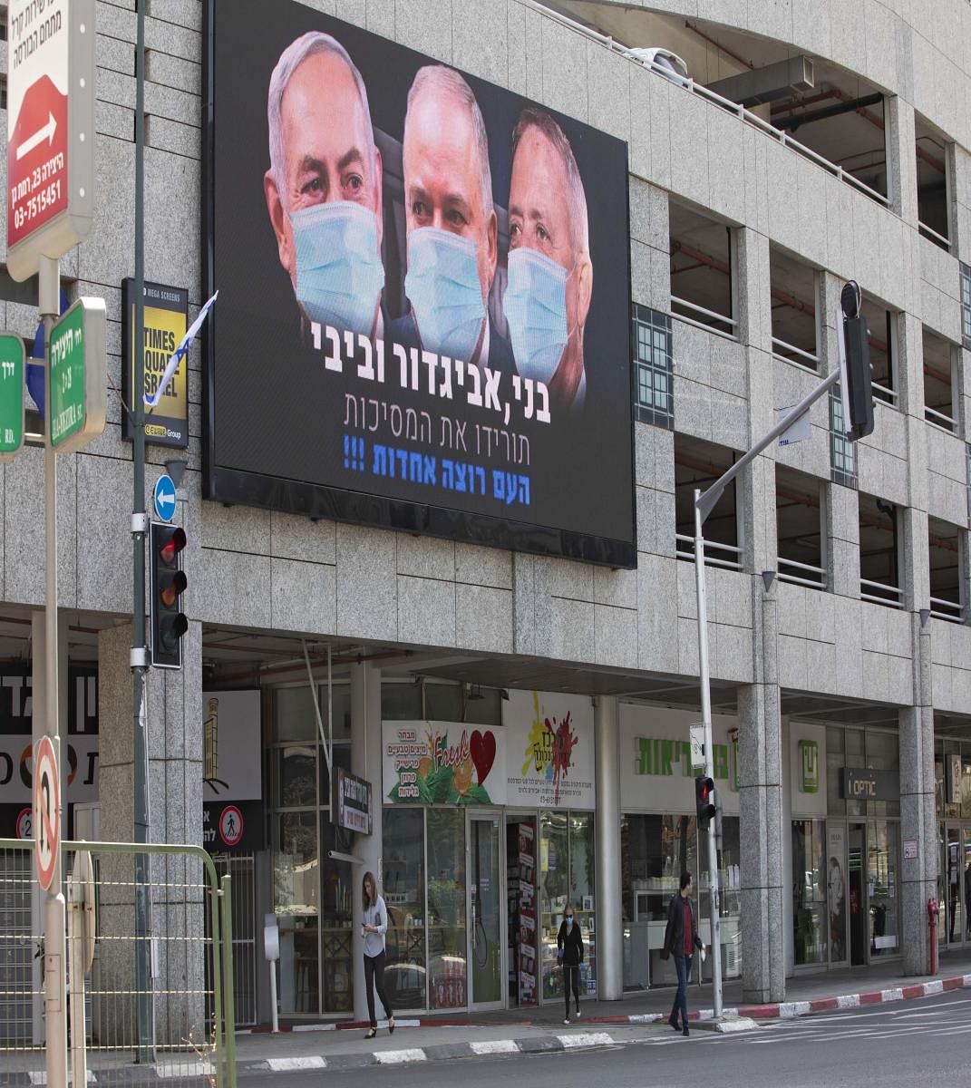 A billboard shows Israeli Prime Minister Benjamin Netanyahu, left, Israeli Former Defense Minister and leader of the Yisrael Beiteinu (Israel Our Home) right-wing party Avigdor Lieberman, center, and Blue and White party leader Benny Gantz, wearing masks in the Israeli city of Ramat Gan, near Tel Aviv. (AFP Photo)