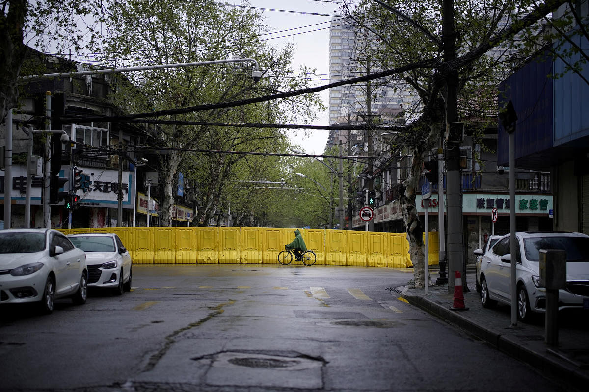 A resident wearing a raincoat rides a bicycle past barriers built up to block a road to a residential area in Wuhan, Hubei province, the epicenter of China's coronavirus disease (COVID-19) outbreak. (Reuters photo)
