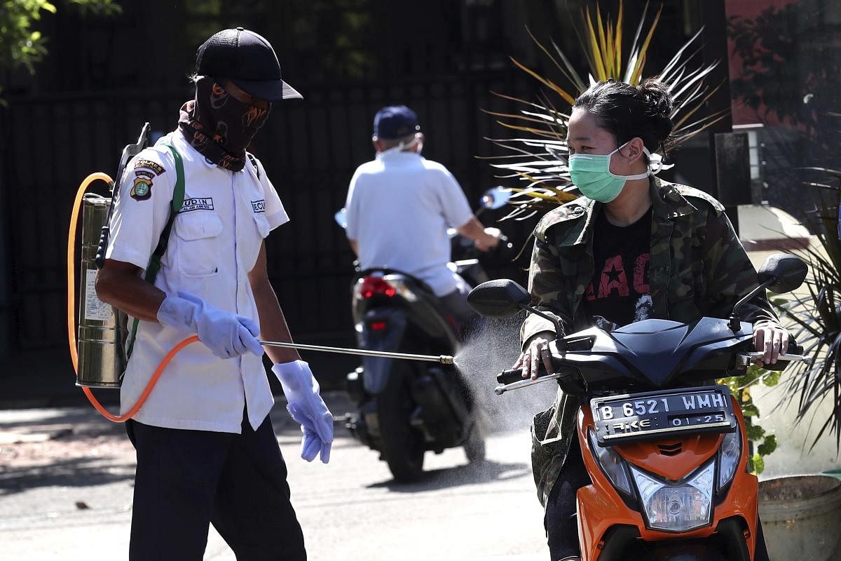 : A motorist is sprayed with disinfectant to help curb the spread of coronavirus in Indonesia (AP Photo)