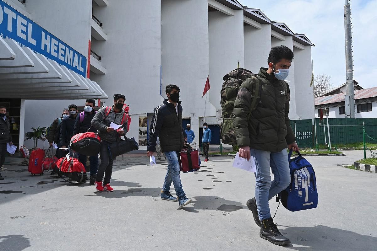 People wearing facemaskswalk with their belongings after completing 14-days of quarantine (AFP Photo)