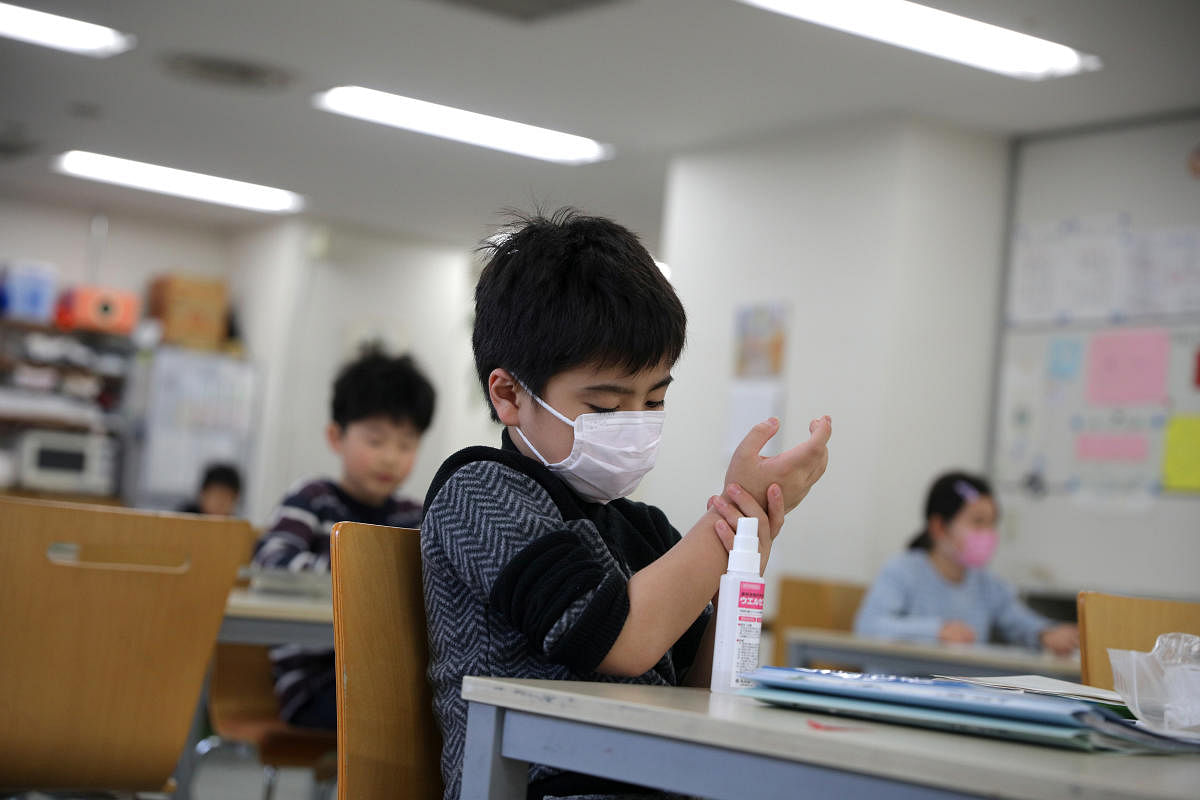 Child, wearing a protective face mask, following an outbreak of coronavirus, uses hand sanitizer at "Stella Kids", daycare center in Tokyo. Credit: Reuters Photo