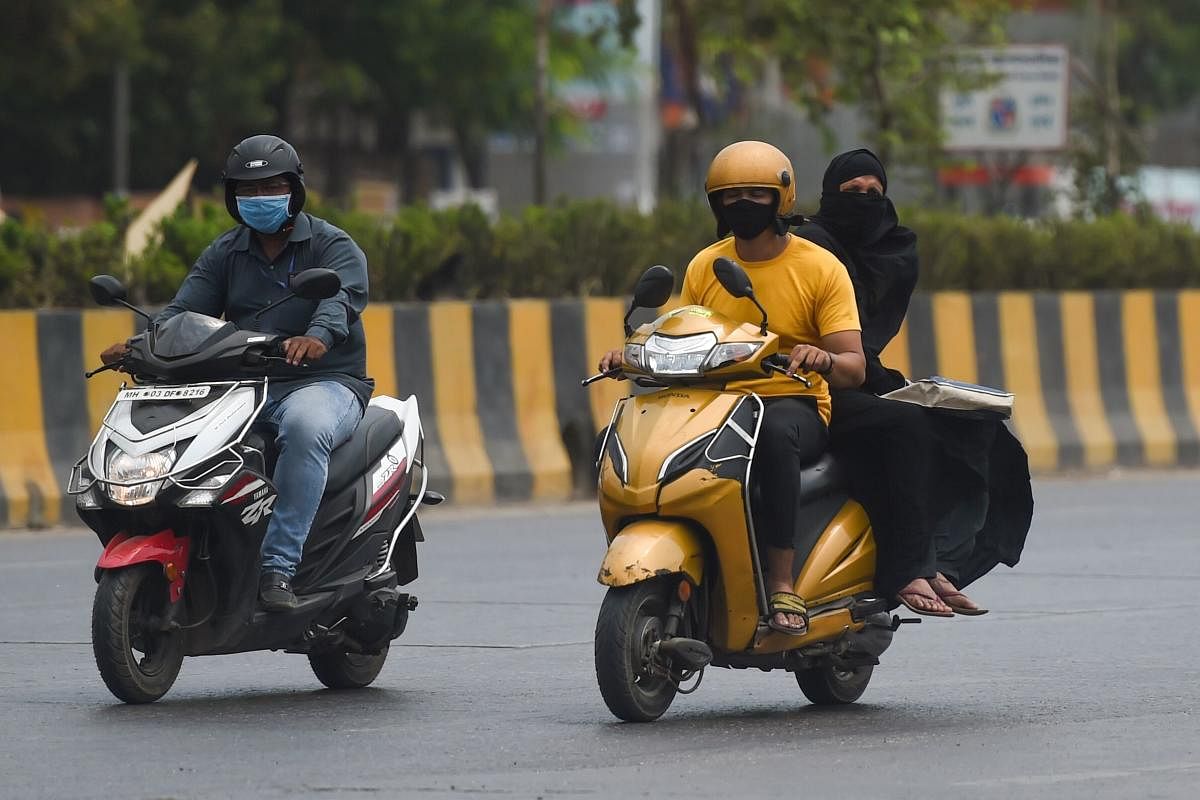 Motorists wearing facemasks ride along a street during a government-imposed nationwide lockdown as a preventive measure against the COVID-19 coronavirus in Mumbai on March 27, 2020. (Photo by Punit PARANJPE / AFP)