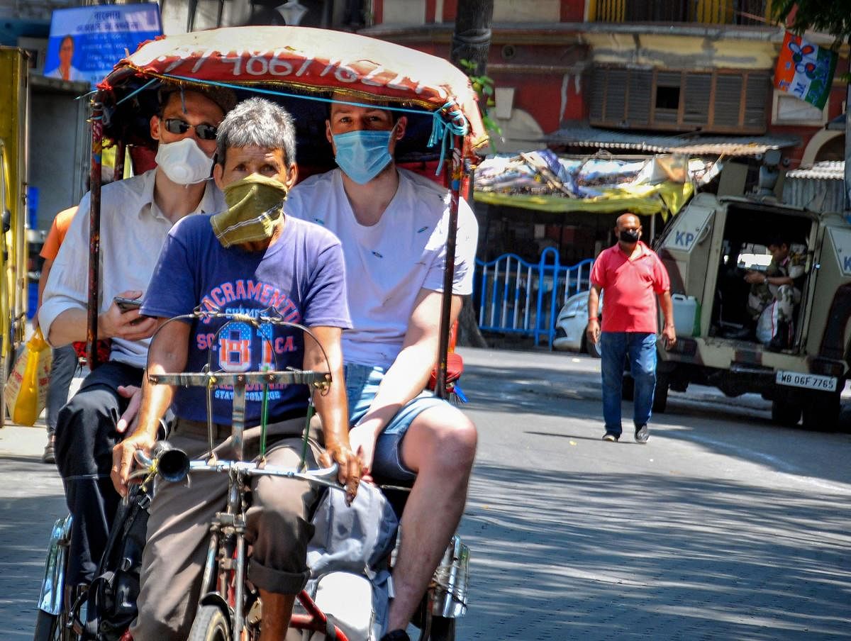A rickshawpuller carries foreign tourists, weaing masks, during the nationwide lockdown in the wake of the coronavirus pandemic, in Kolkata. (PTI Photo)
