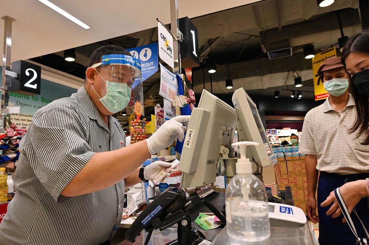 A cashier wearing a face mask and rubber gloves, as a preventive measure against COVID-19. AFP