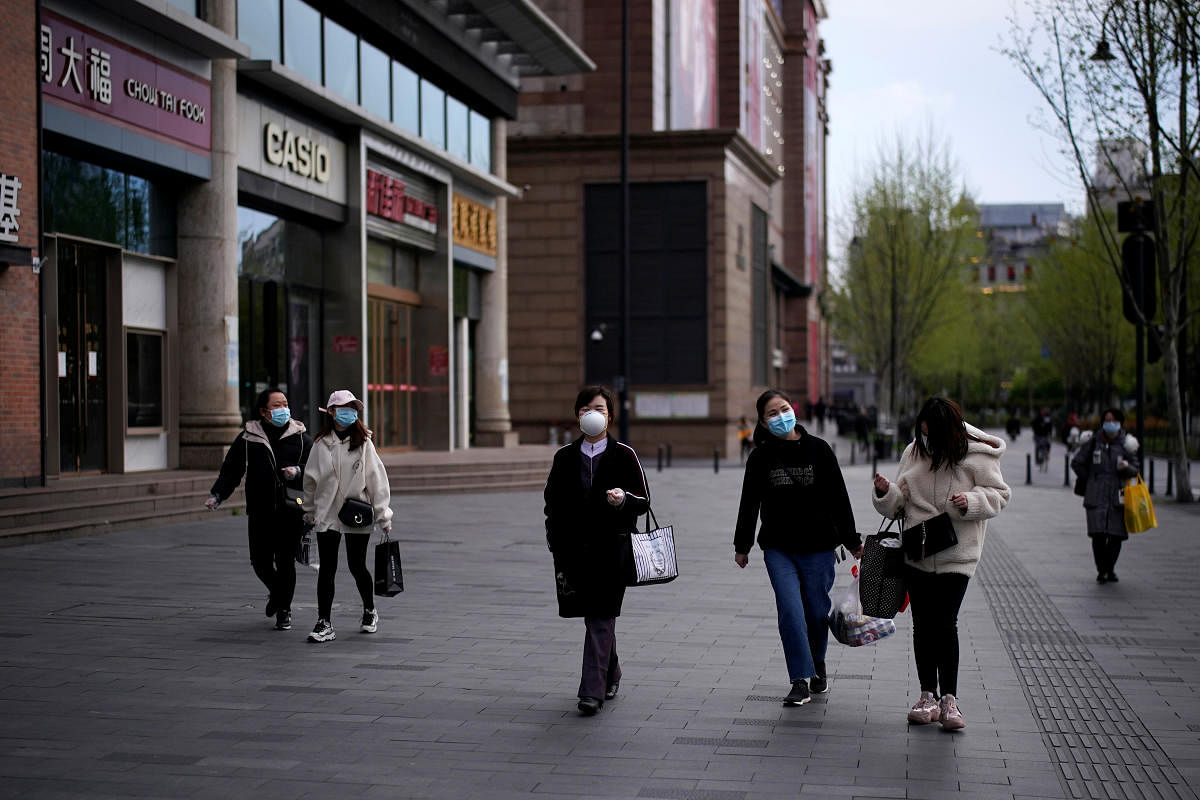 People wearing face masks walk at a shopping area in Wuhan, Hubei province, the epicenter of China's coronavirus disease (COVID-19) outbreak