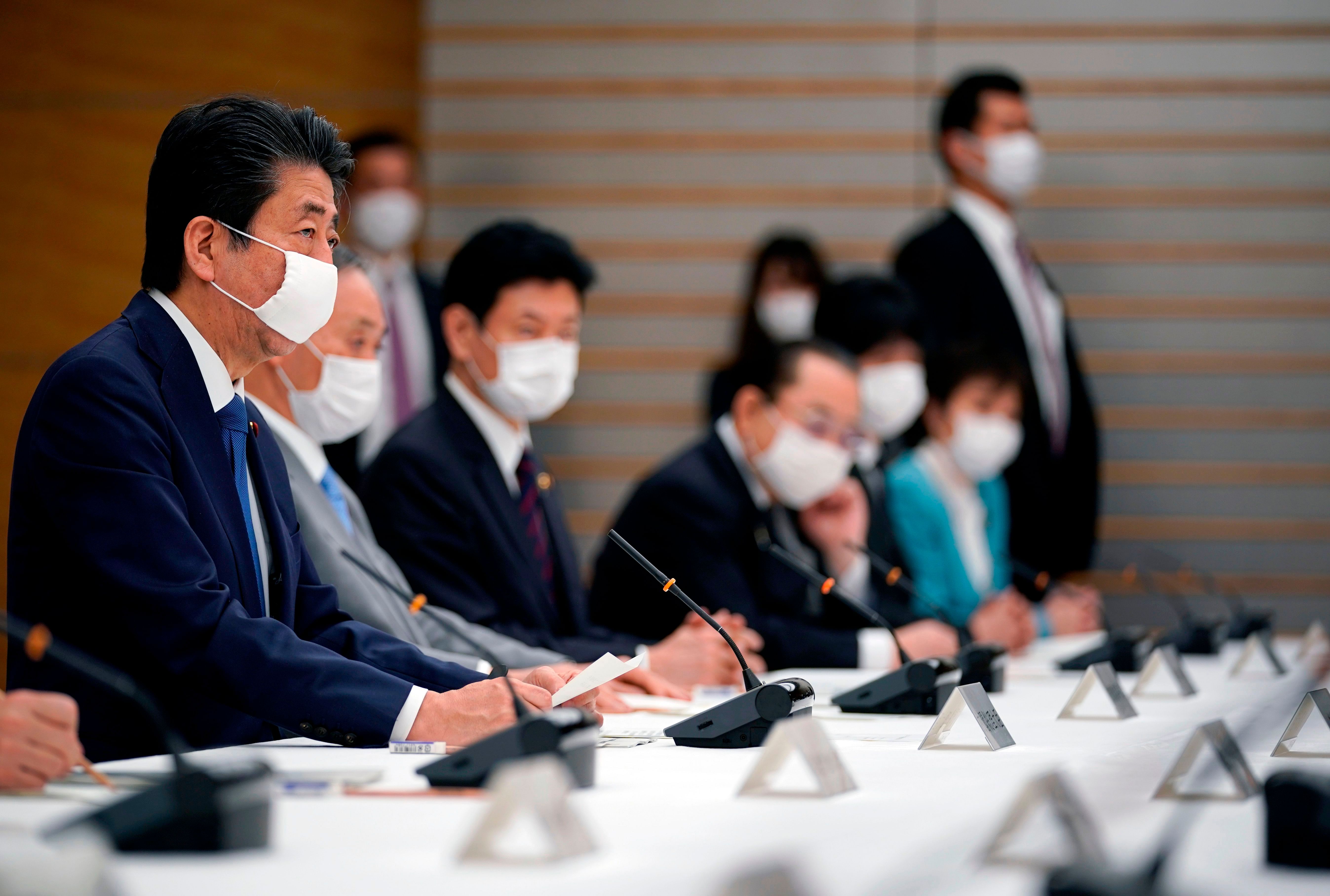  Japan's Prime Minister Shinzo Abe (L) speaks during a meeting at the headquarters for measures against the novel coronavirus disease. (Credit: AFP)