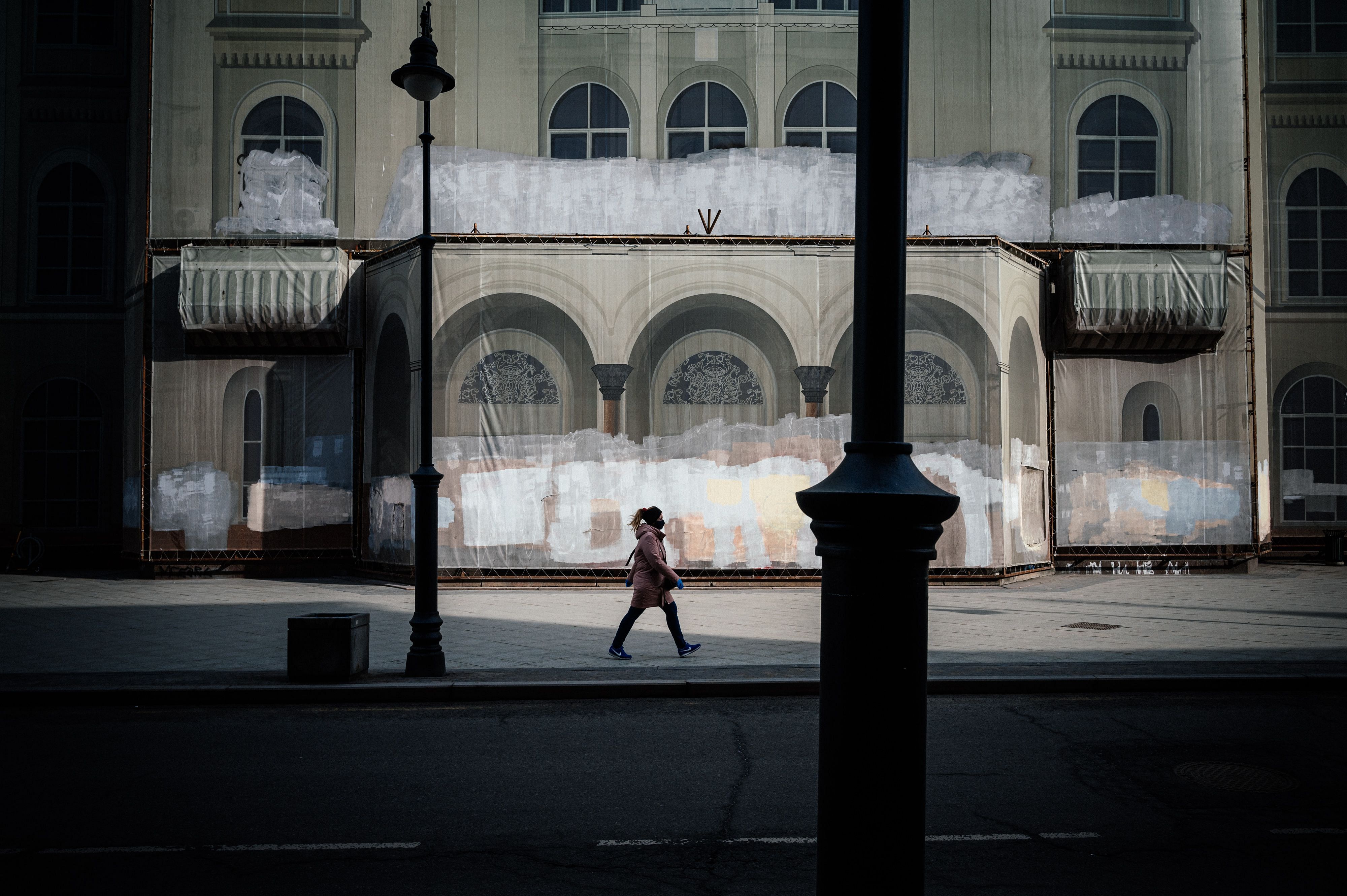A woman wearing a face mask and protective gloves walks along an empty street in downtown Moscow. (Credit: AFP)