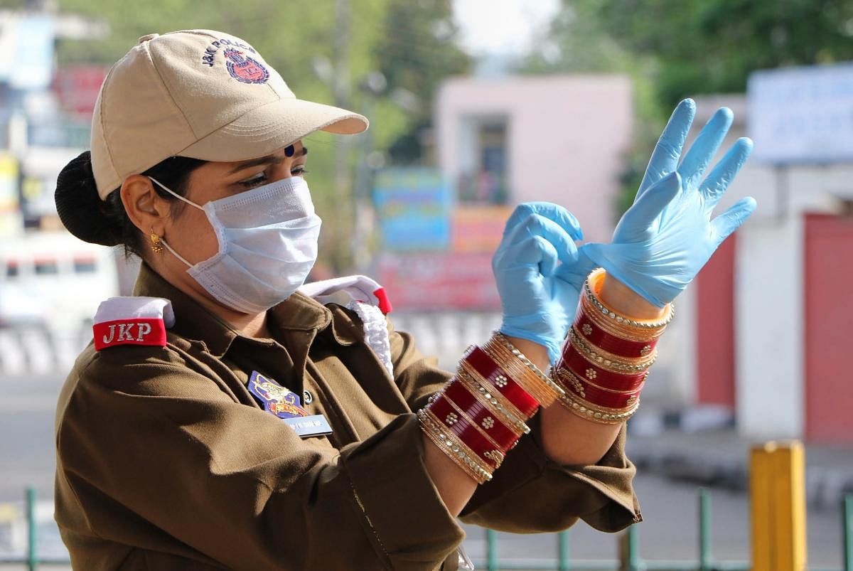 A policewoman wears gloves as she stands to perform her duty, during a nationwide lockdown, imposed in the wake of coronavirus pandemic, in Jammu, Saturday , March 28, 2020. (PTI Photo)