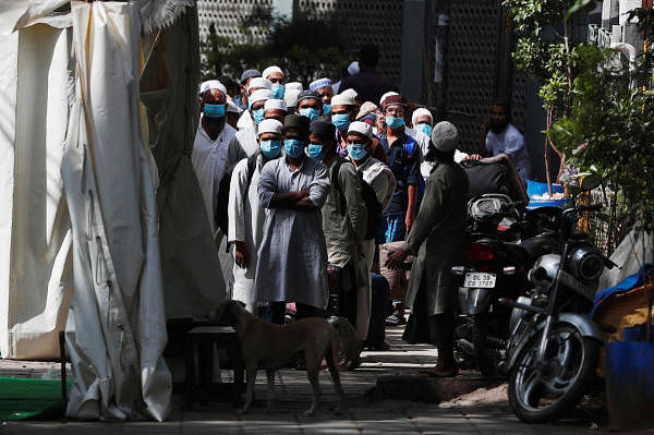 Men wearing protective masks wait for a bus that will take them to a quarantine facility, amid concerns about the spread of coronavirus disease (COVID-19), in Nizamuddin area of New Delhi, India, March 31, 2020. (Credit: Reuters Photo)