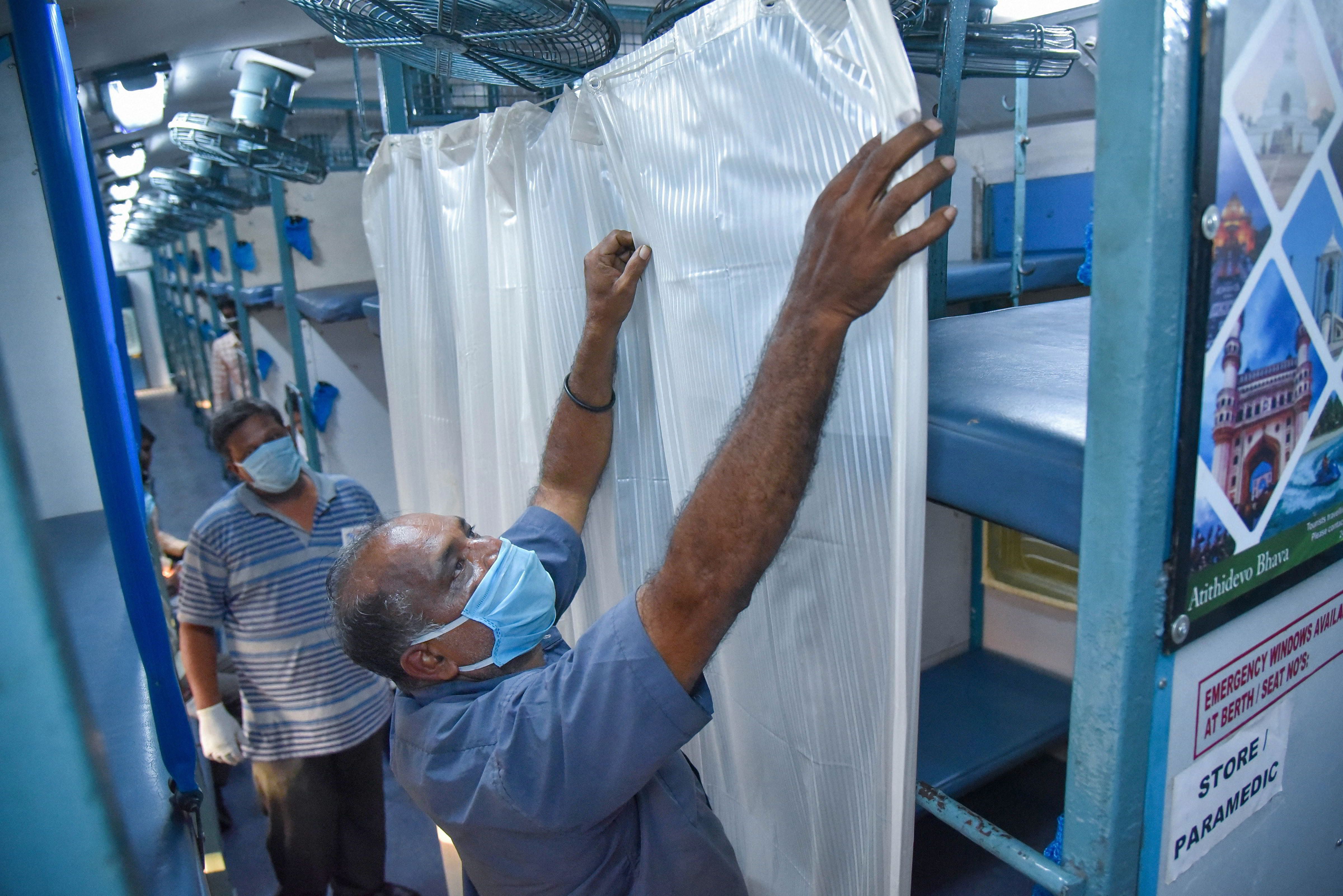 Workers put curtains on railway coaches to be converted into isolation wards for COVID-19 patients, during the nationwide lockdown. (PTI Photo)
